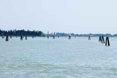 Tranquil seascape with wooden poles and distant shoreline.の写真素材