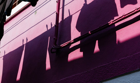 Cinematic shadows on a pink wall with geometric patterns and playful light.
