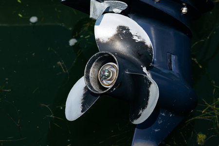 Close-up of boat propeller in water with algae.