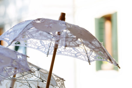 Elegant lace parasols in sunlit scene near mediterranean architecture.の写真素材