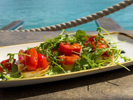 Fresh bruschetta with arugula and cherry tomatoes by the sea.の写真素材