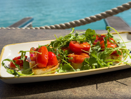 Fresh tomato and arugula bruschetta by the seaside.の写真素材