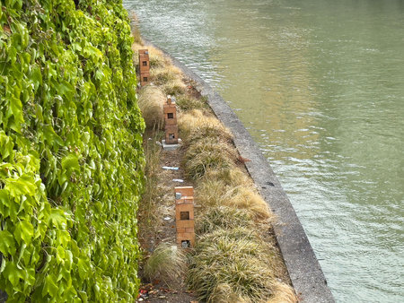 Brick birdhouses along ivy-covered riverside path.の写真素材