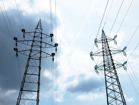 High voltage power lines against blue cloudy sky.の写真素材