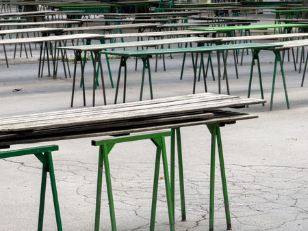 Empty outdoor wooden tables on green metal frames in urban setting.の写真素材