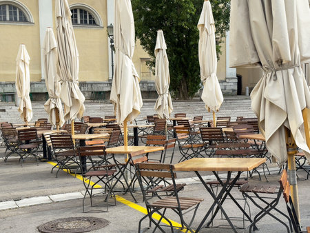 Outdoor cafe with wooden tables and closed umbrellas in urban setting.の写真素材