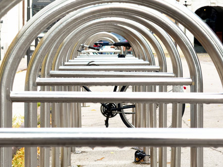 Symmetrical rows of metallic bike racks with bicycle on urban street.