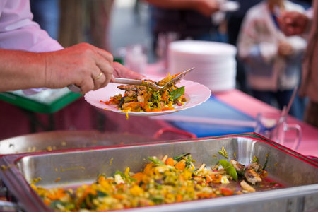 Street food fest: fresh vegetable and fish dish served outdoors by caucasian adult.の写真素材
