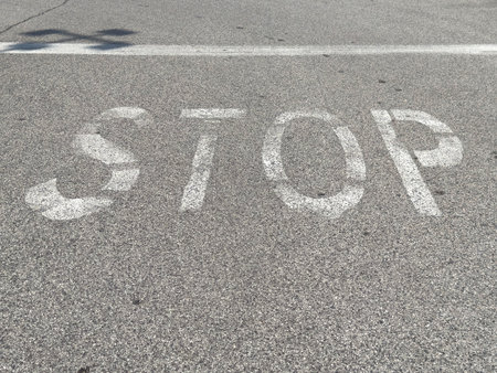 Faded stop sign on asphalt surface in afternoon sunlight.の写真素材