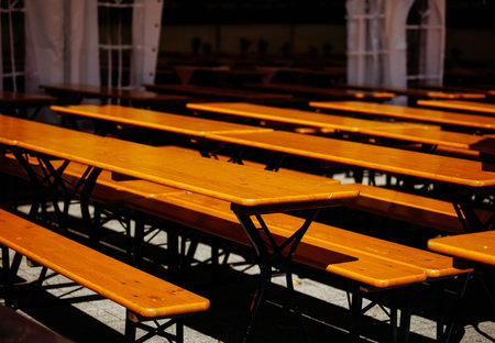 Sunlit outdoor wooden tables and benches in a pavilion setting.