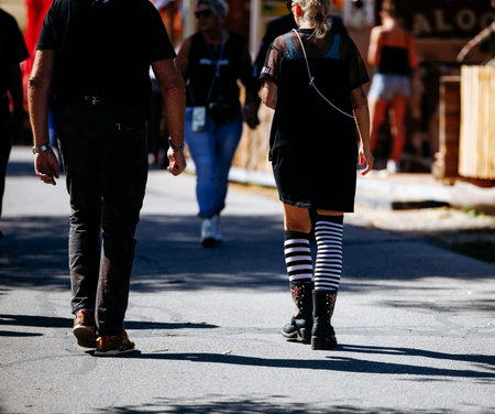Caucasian adults walking outdoors in casual attire at daytime event.の写真素材