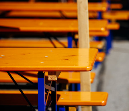 Close-up of orange outdoor picnic tables and benches in sunlight.の写真素材