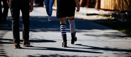 Caucasian adults walking on street with striped socks in urban setting.の写真素材