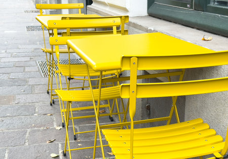 Bright yellow outdoor bistro furniture on paved street.の写真素材