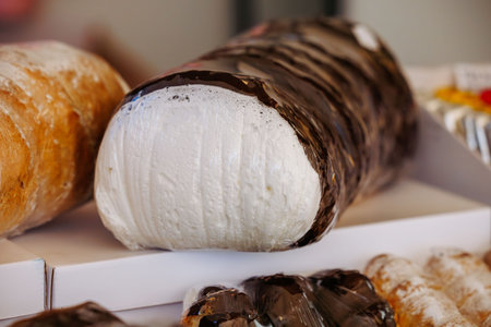 Large marshmallow coated with chocolate on display at a market.の写真素材