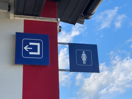Outdoor restroom signage with blue lady symbol against cloudy sky.の写真素材