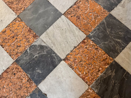 Intricate checkerboard tile pattern with orange and gray marble.の写真素材