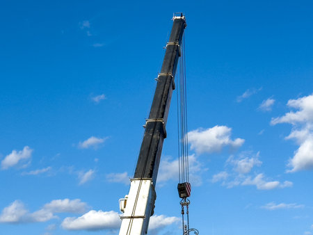 Crane arm against blue sky with clouds.の写真素材