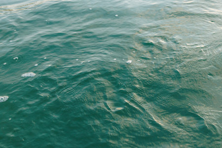 Calm ocean water surface with gentle ripples and bubbles.の写真素材