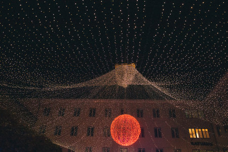 Outdoor ice rink features a stunning display of twinkling lights and a prominent red ornament, enhancing the lively winter ambiance with skaters enjoying the sceneの写真素材