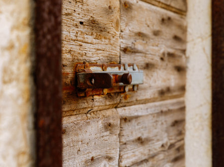 Rustic wooden door latch with weathered texture and metal bolt detail.の写真素材