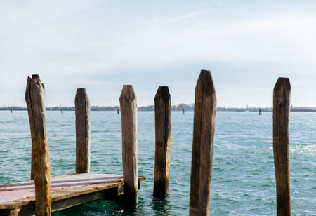 Serene lake pier scene with wooden posts and calm water.の写真素材
