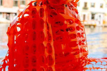 Bright orange safety netting with circular patterns by waterfront.の写真素材