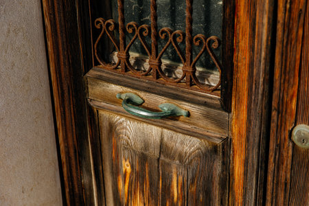 Rustic wooden door with iron grate and metal handle.の写真素材