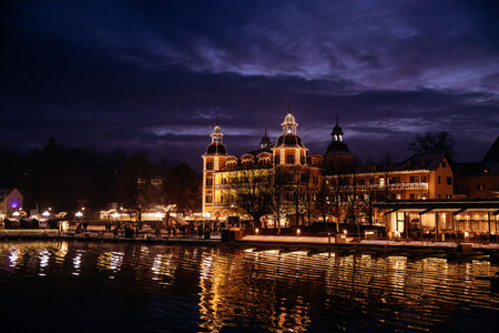 Velden, Austria - December 20, 2024: Schlosshotel am Woerthersee is beautifully lit at night during winter advent, with festive decorations and shimmering reflections on the lakeの写真素材