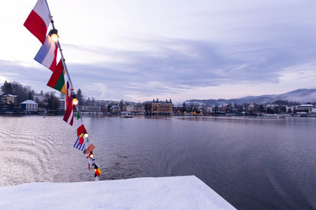 Velden, Austria - December 20, 2024: Schlosshotel am Woerthersee showcases festive lights and flags, creating a magical winter atmosphere by the tranquil lake during Advent timeの写真素材