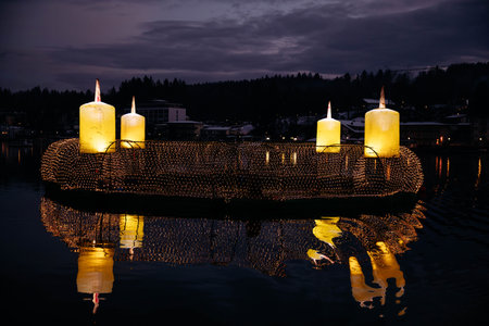 Velden, Austria - December 20, 2024: Schlosshotel am Woerthersee features glowing candles on water, enhancing the winter ambiance during Advent with beautiful reflections and holiday spiritの写真素材