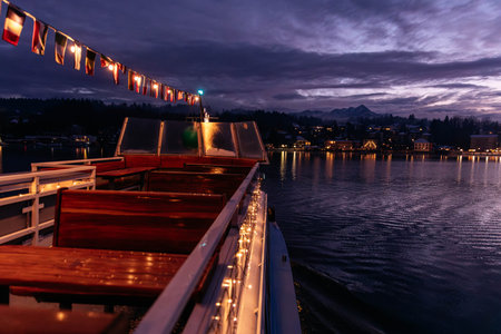 Velden, Austria - December 20, 2024: Schlosshotel am Woerthersee showcases winter beauty with festive lights illuminating the water, creating a serene ambiance during Adventの写真素材