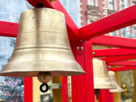 Brass bells hanging on red wooden structure outdoors in urban setting.の写真素材