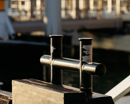 Close-up of weathered metal bollard at dock with sunlight and shadows.