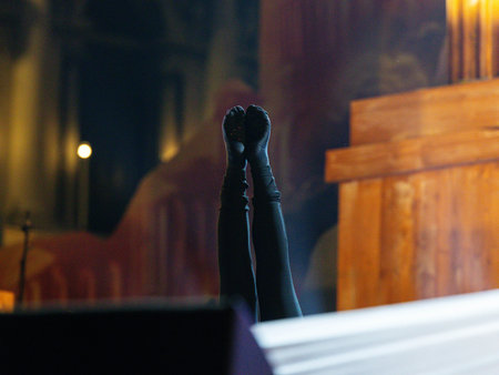 Upside-down legs in black socks on stage with wooden background.