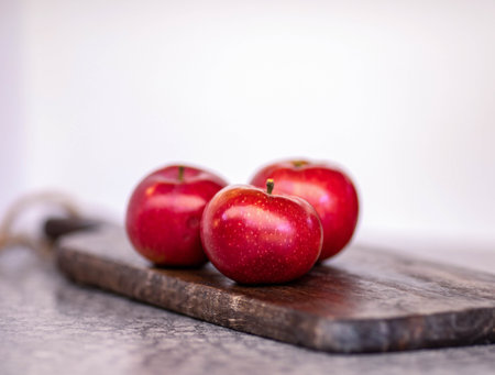 Fresh red apples on rustic wooden cutting board.