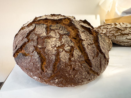 Crusty artisan dark rye bread on kitchen counter.