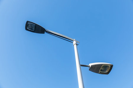 Modern street lamp against clear blue sky.
