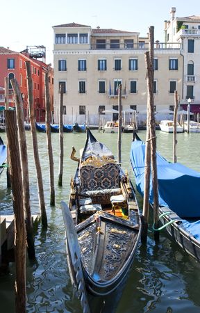Gondola in Venice. A large black boat is richly decorated with carvings and gold detail stands at the canal Grandeの写真素材