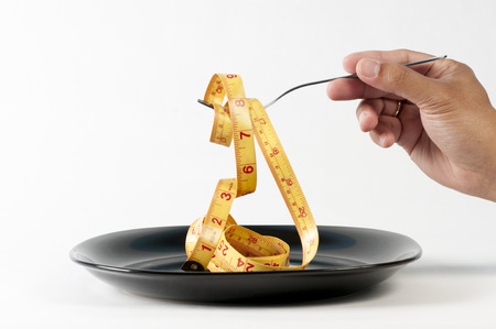 A hand lifting a tape measure on a plateの写真素材