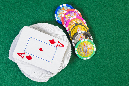 Deck of twisted card with poket chips on top of green table surfaceの写真素材