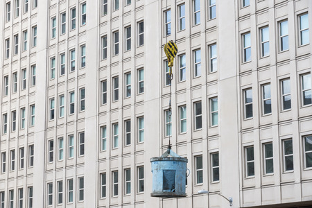 Cable lifting a concrete bucket with building in the back groundの写真素材