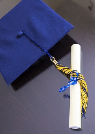 Graduation cap with rolled diploma on brown background.の写真素材