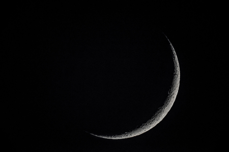 Waxing crescent moon over dark sky background.の写真素材