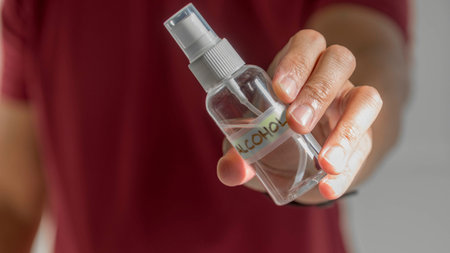Hand giving over a bottle of alcohol disinfectant.