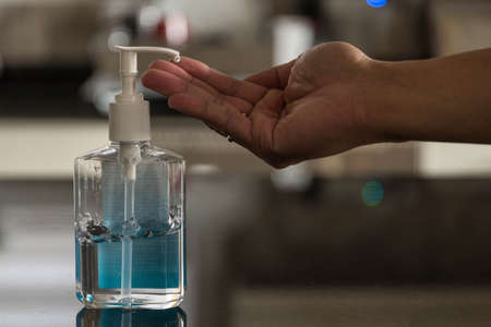 A Hand reaching for hand sanitzer dispenser.の写真素材