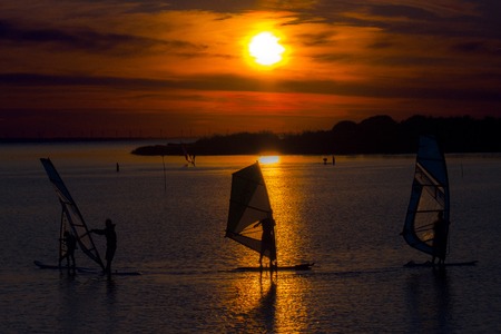 Surfing Sunset. Colored silhouettes of surfers on the waterの写真素材