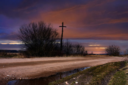 Country road at dusk and wooden crossの写真素材