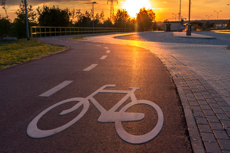 A bicycle path in the city marked with a symbol, the setting sun illuminates the bicycle signの写真素材
