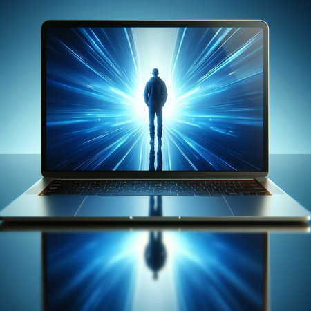 Man in front of a laptop with blue rays on the screen.の素材